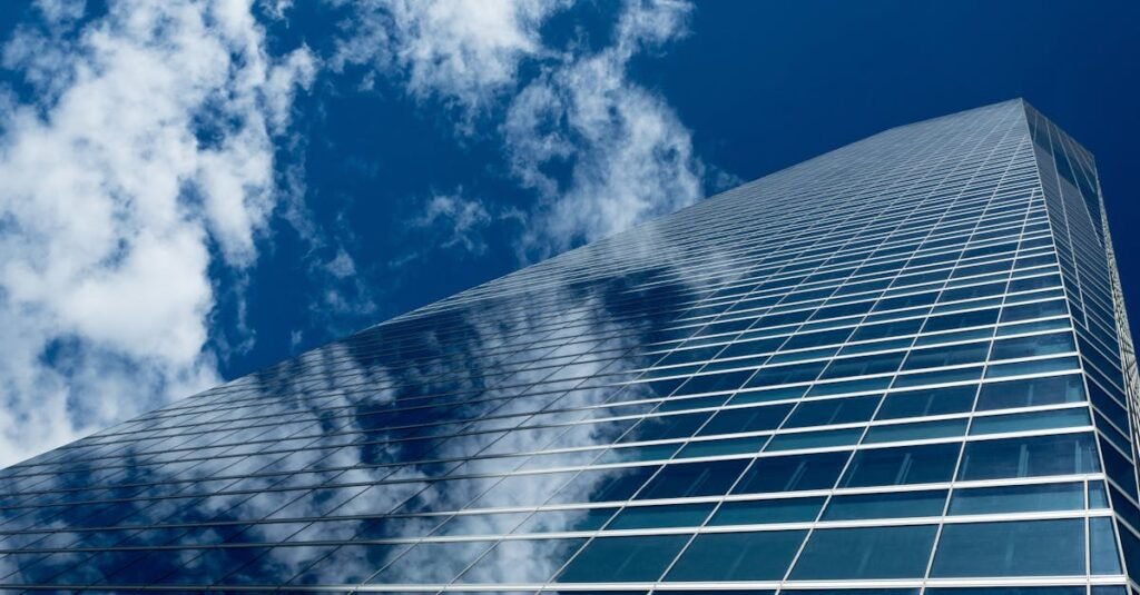 Low-angle view of a modern skyscraper with reflective glass windows against a blue sky.